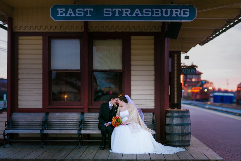 Bride and groom on bench at Strasburg Train Station .