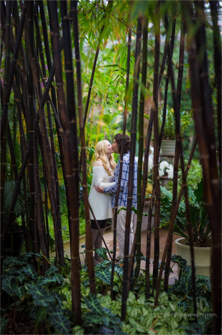 Engagement photo of couple kissing through bamboo stalks at longwood gardens.