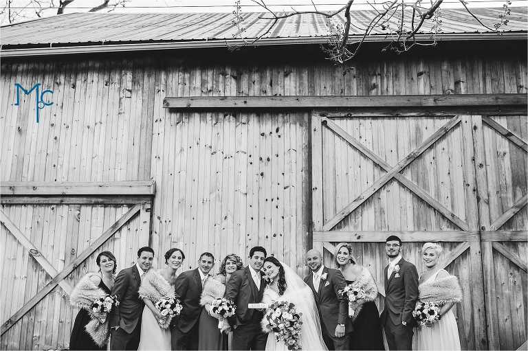 Black and white Wedding party photo in front of rustic barn at Indian Orchards